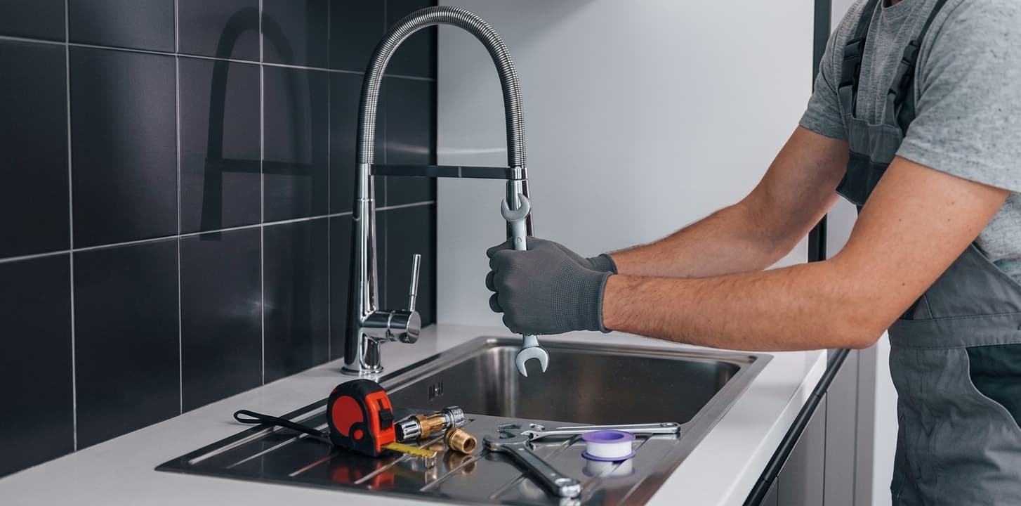 Close-up of a plumber repairing a kitchen faucet