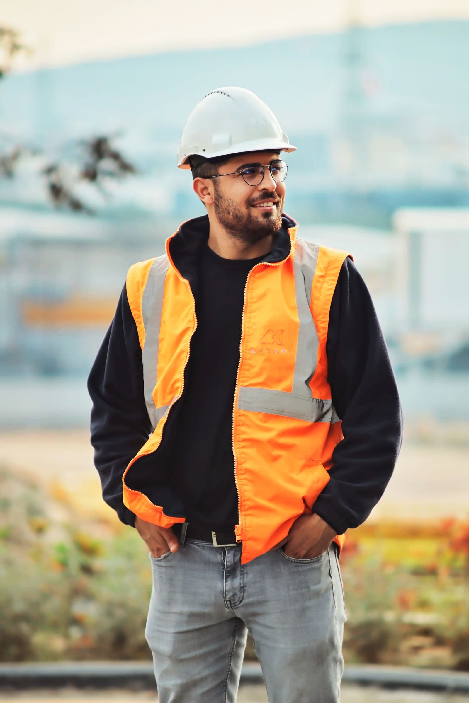 Professional roofer in safety helmet and vest standing confidently on site